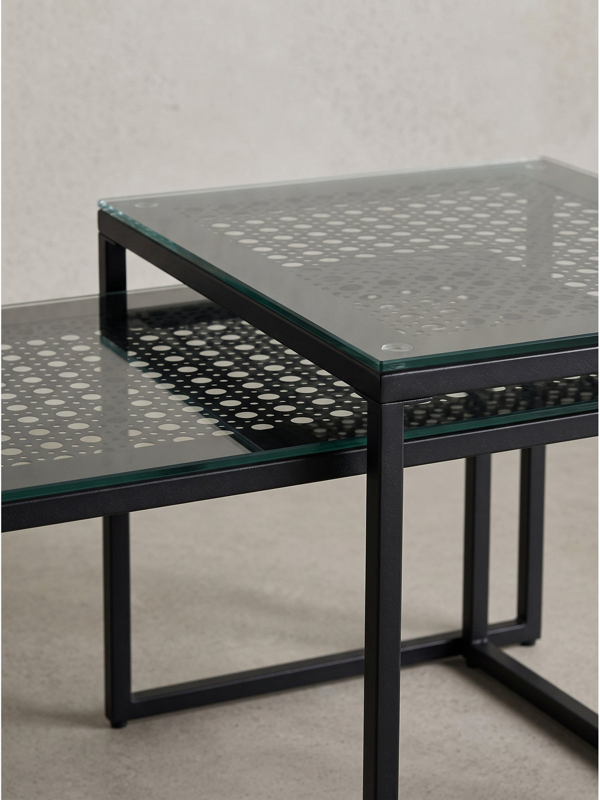Gesamteindruck der architektonischen Sofatische aus schwarzem Stahl und gemustertem Glas für platzsparende Einrichtungskonzepte._