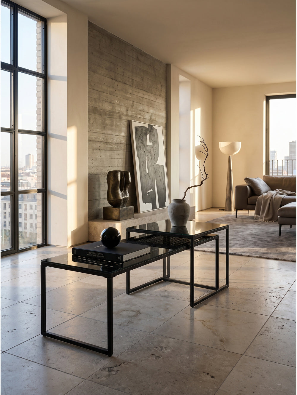 Schwarzes Satztisch 2er Set aus Glas und Metall im modernen Wohnzimmer vor einer rohen Sichtbetonwand._