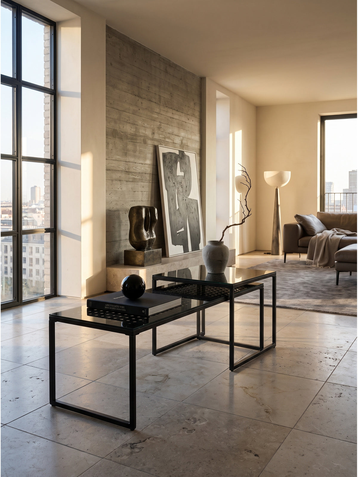 Schwarzes Satztisch 2er Set aus Glas und Metall im modernen Wohnzimmer vor einer rohen Sichtbetonwand.