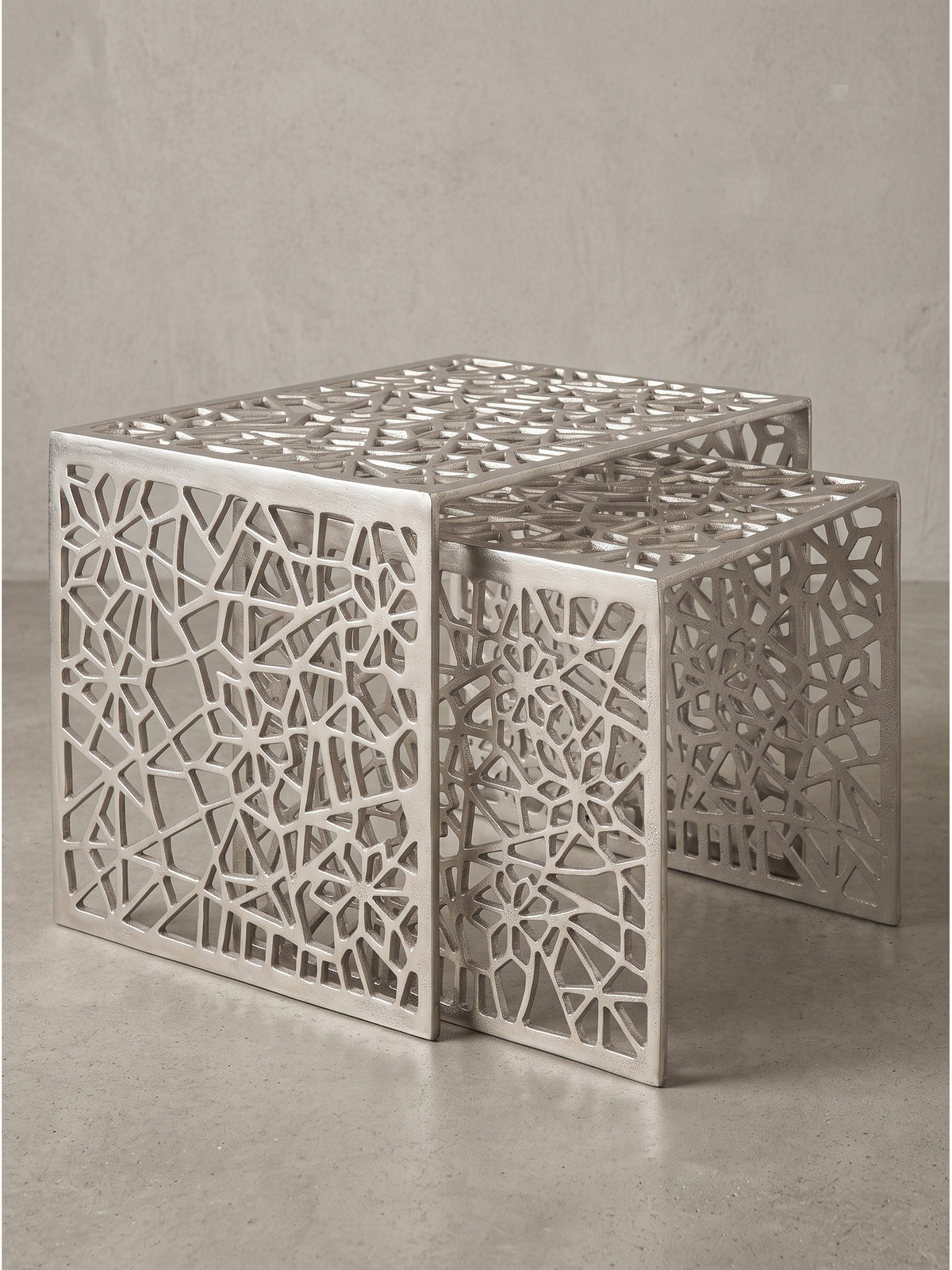 Rechteckiger Loungetisch aus glänzendem Aluminium im 2er-Set mit unregelmäßigem Spinnennetz-Muster vor neutralem weißen Hintergrund_