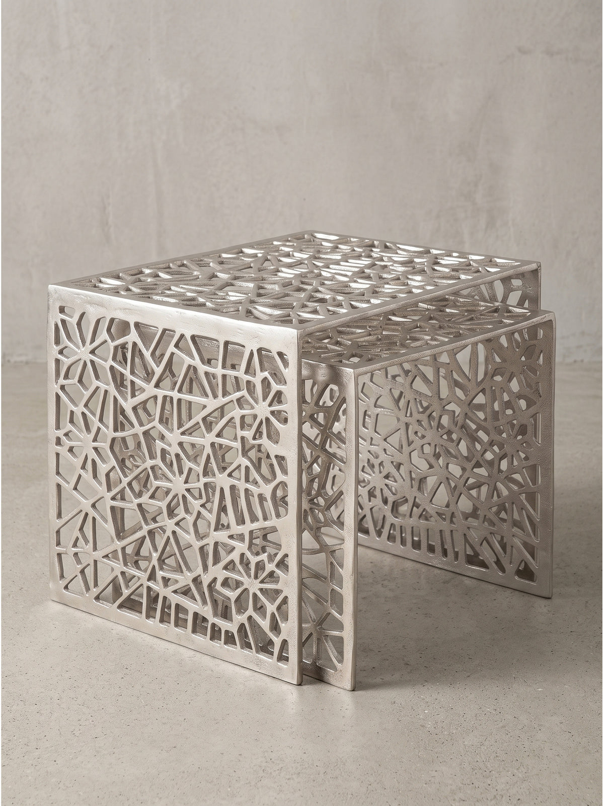 Makro-Detail der unteren Kanten des silbernen Beistelltisches, massives Aluminium mit feinen Schattierungen im abstrakten Gittermuster_