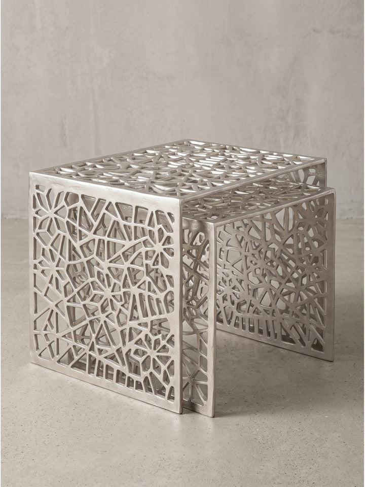 Makro-Detail der unteren Kanten des silbernen Beistelltisches, massives Aluminium mit feinen Schattierungen im abstrakten Gittermuster_