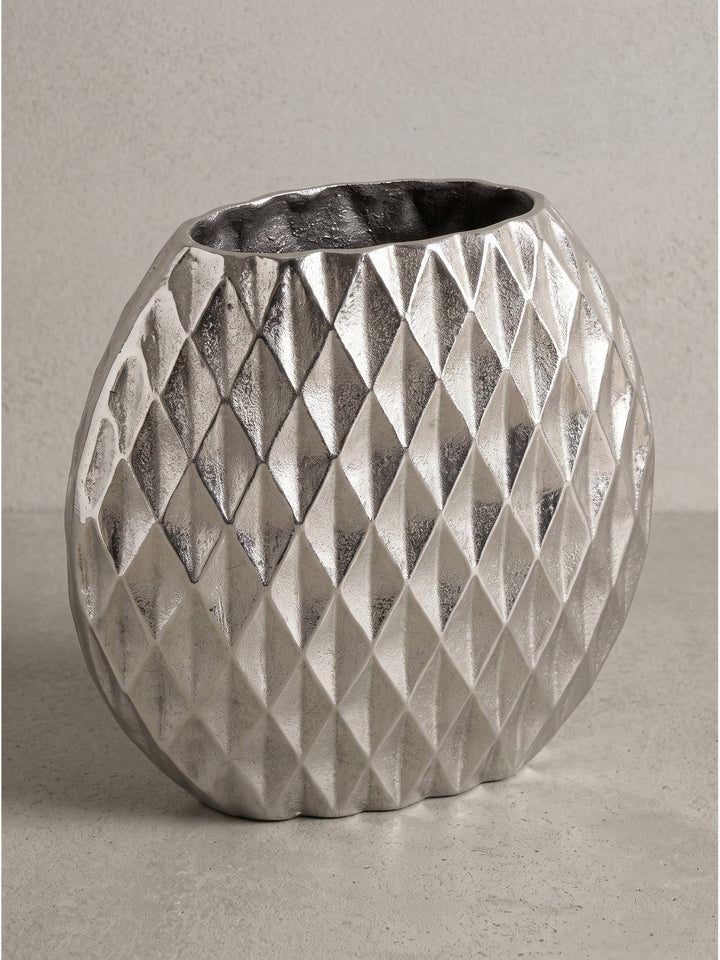 Detailansicht der markanten Rautenstruktur auf der kühlen Oberfläche der silbernen Aluminium-Vase im modernen Design._
