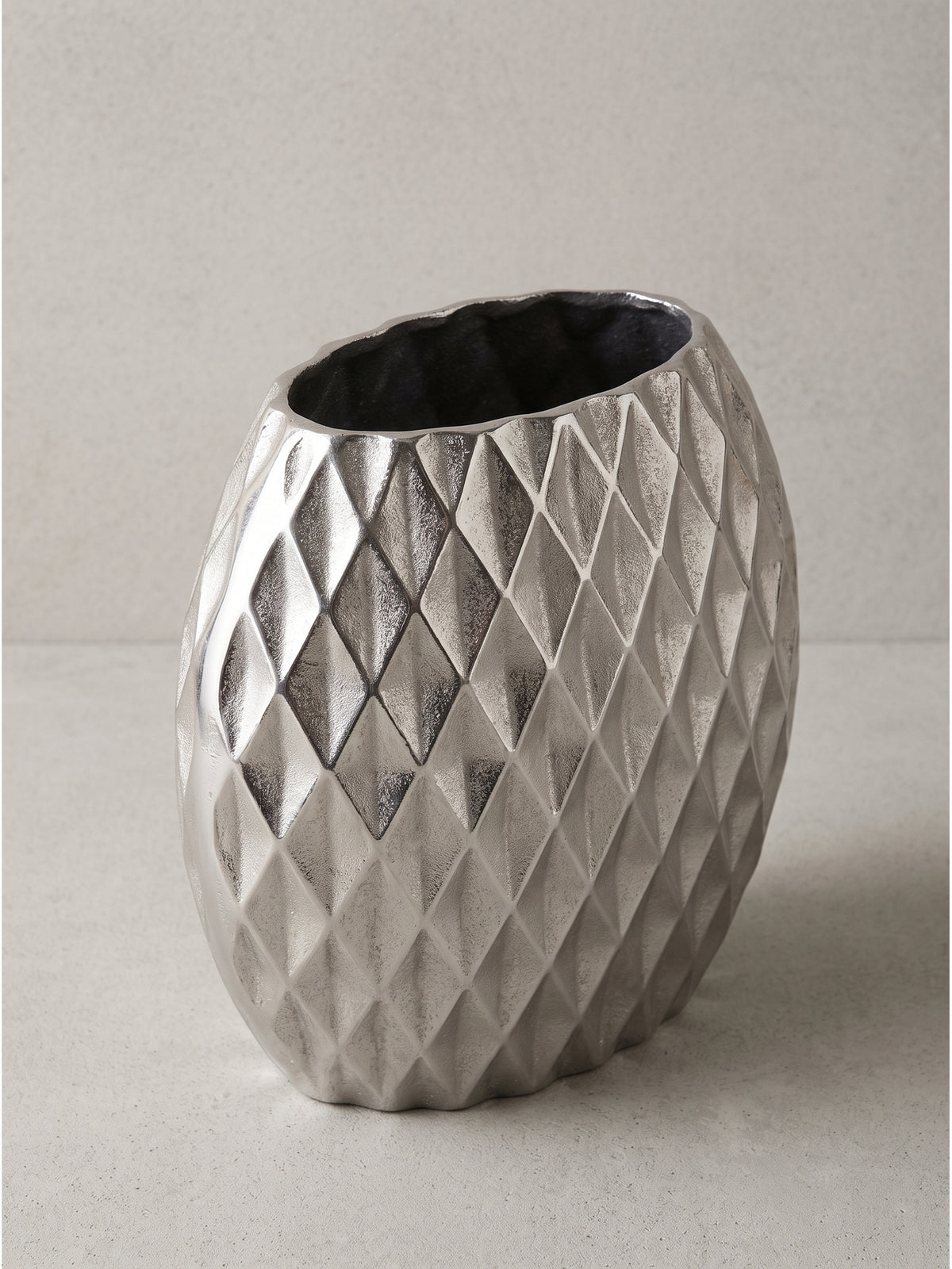 Flache Tischvase aus silbernem Aluminium 34x13x32 cm mit markantem Rautenmuster in der Frontalansicht vor weißem Hintergrund._