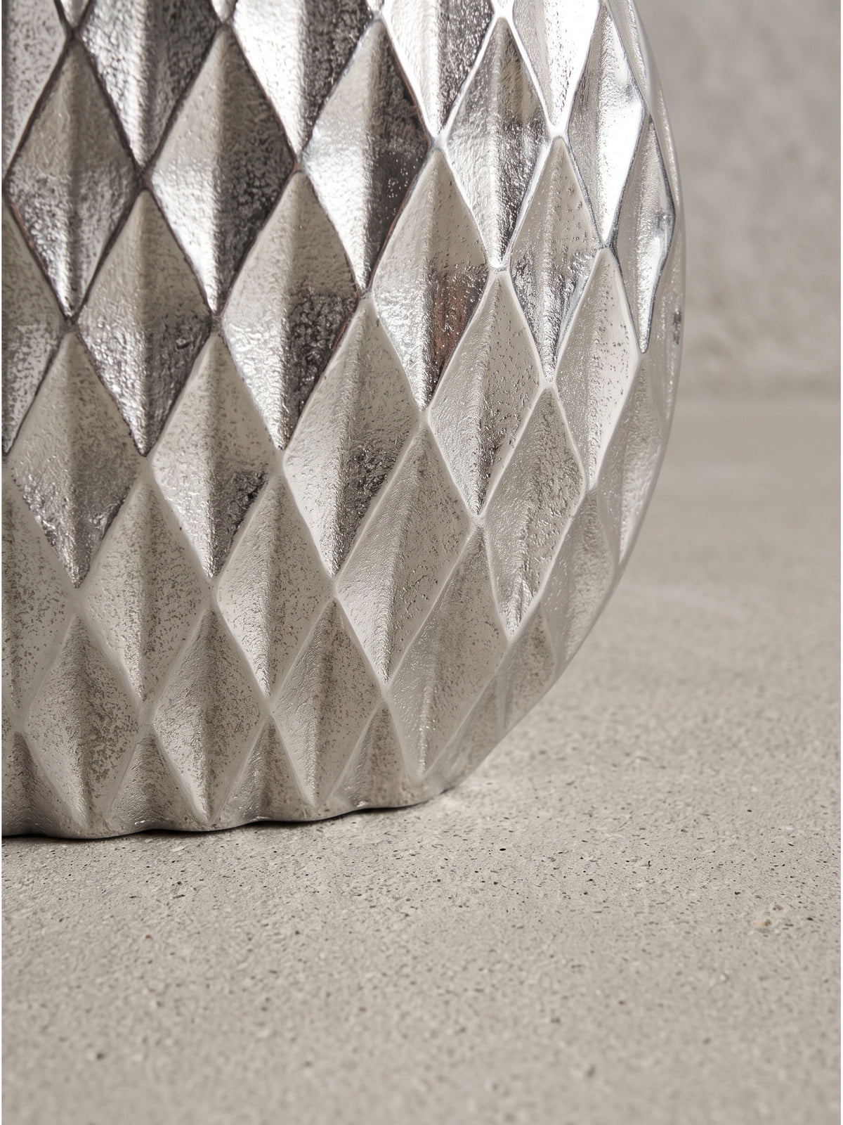 Alternative Perspektive der modernen Alu-Vase in Silber, deren glänzende Oberfläche kühle Lichtreflexe in der Umgebung erzeugt._
