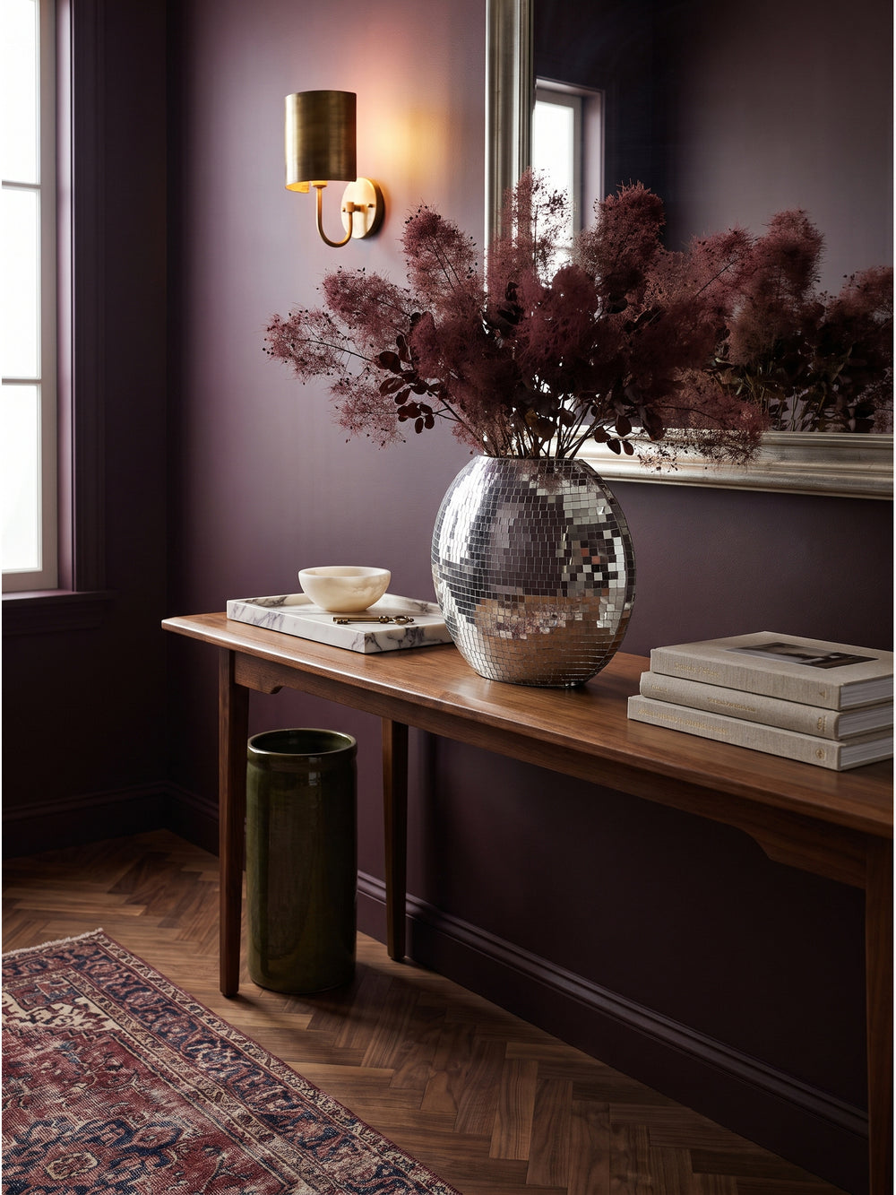 Silberne Design Vase auf einem dunklen Holztisch arrangiert mit Leinenbüchern und antiken Messingschlüsseln im Wohnbereich_