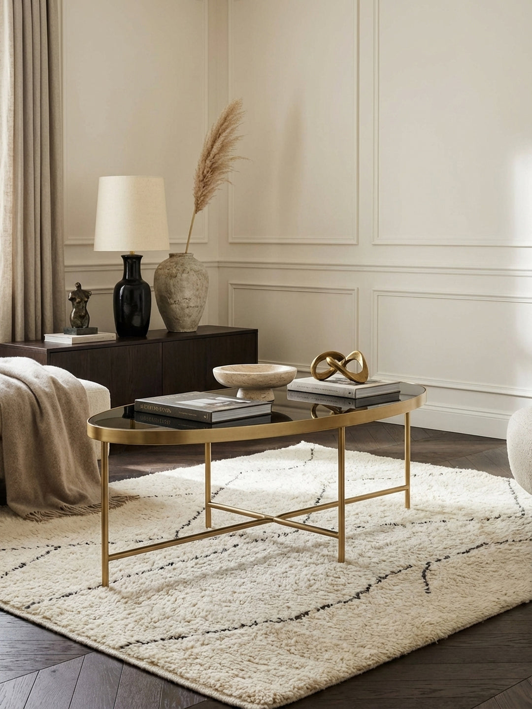 Eleganter ovaler Couchtisch mit schwarzer Glasplatte und goldenem Gestell, Mittelpunkt einer modernen Sitzgruppe in einem hellen, luxuriösen Wohnzimmer._