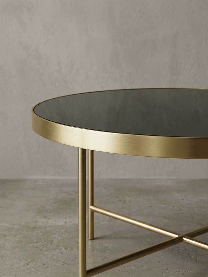 Detailaufnahme des filigranen X-Gestells des Design Couchtisches, das die hochwertige, matte Lackierung des goldenen Stahls in den Vordergrund stellt._