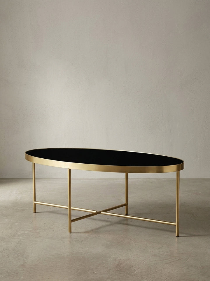 Seitenansicht des Wohnzimmertisches, der die schlanke Silhouette und die Höhe von 40 cm des goldenen Metallgestells mit der schwarzen Glasplatte perfekt darstellt._