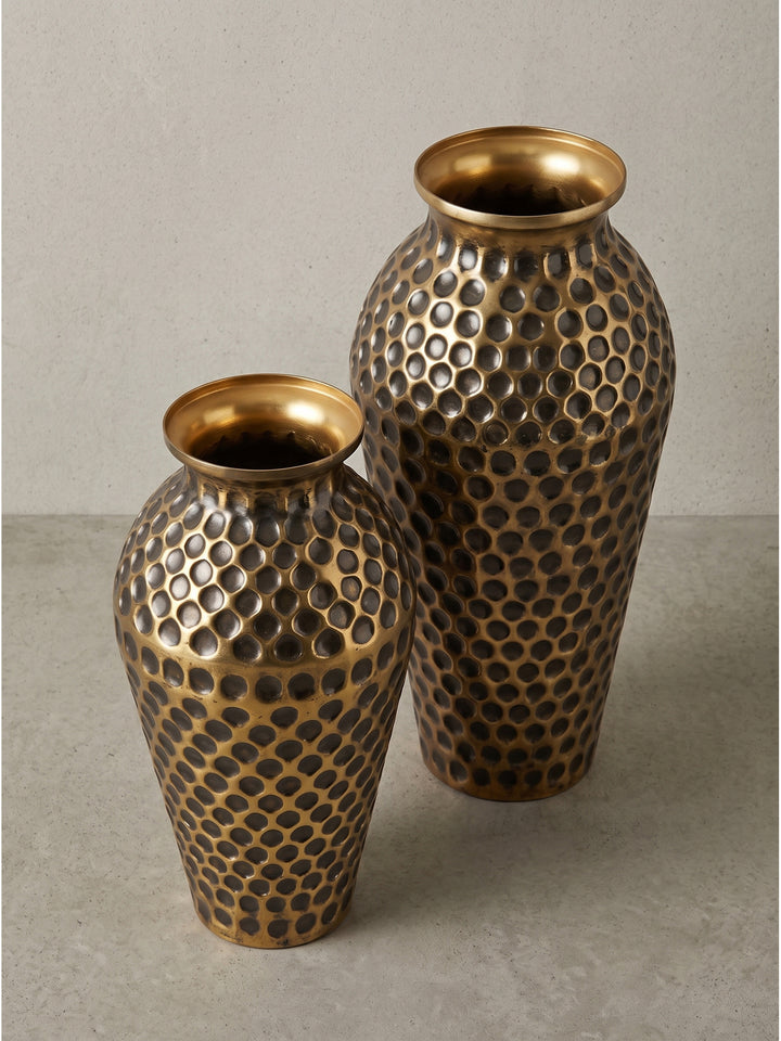Fokus auf den abgerundeten oberen Rand der Deko Vase aus Aluminium in Gold neben minimalistischer Wandkunst_