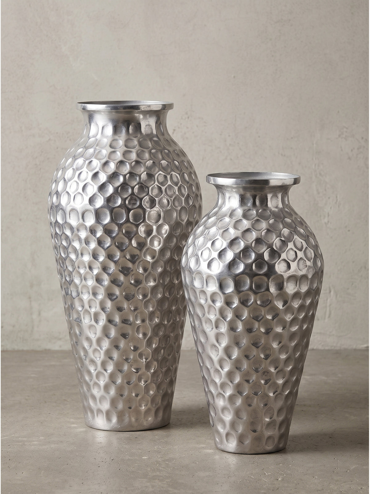 Frontalansicht des zweiteiligen Deko Vasen Sets aus gehämmertem Aluminium in klassischer Amphorenform vor neutralem Hintergrund._