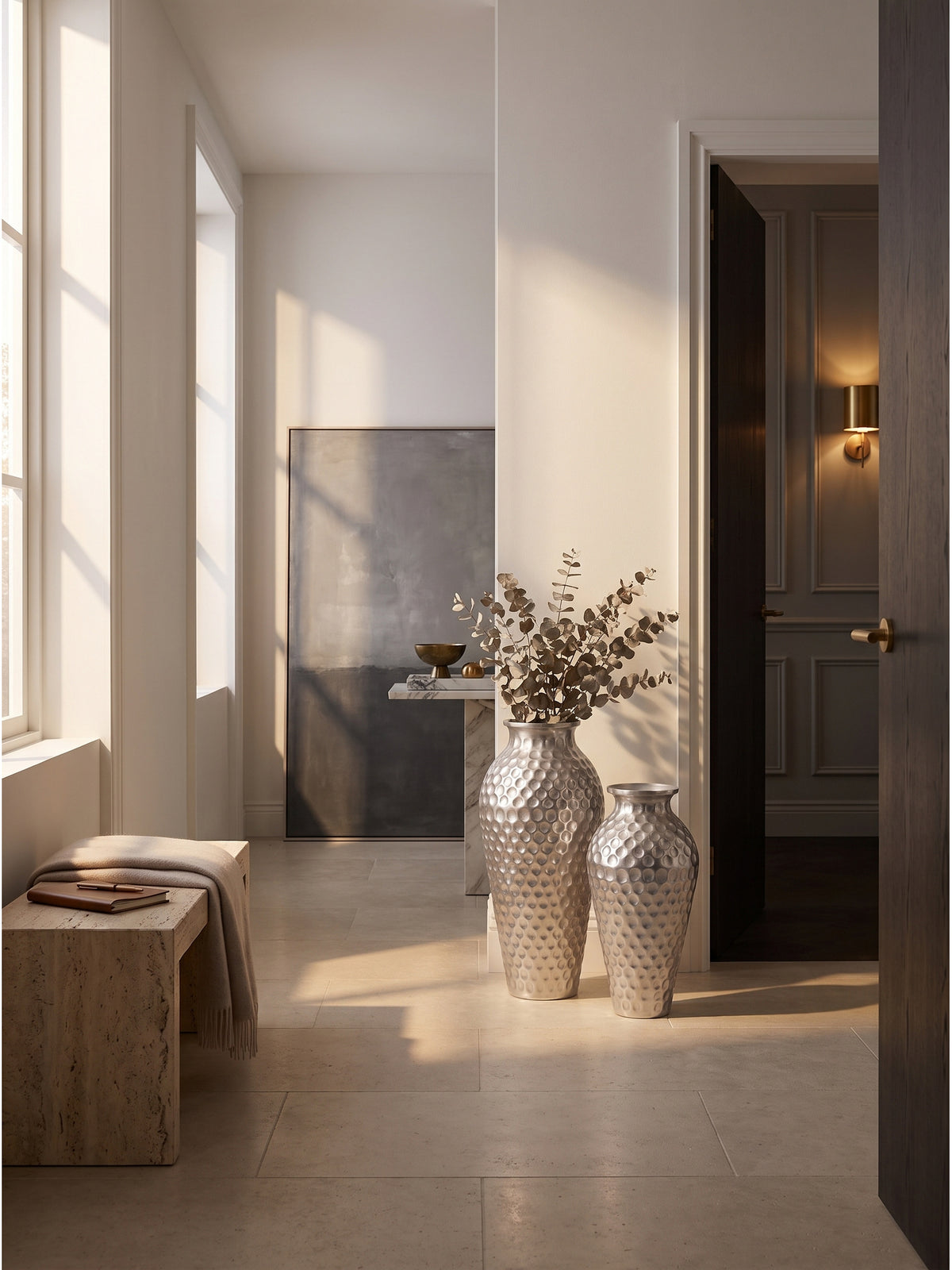 Zwei handgefertigte Deko Vasen aus gehämmertem Aluminium in Silber auf einem großformatigen Kalksteinboden im puristischen minimalistischen Foyer.
