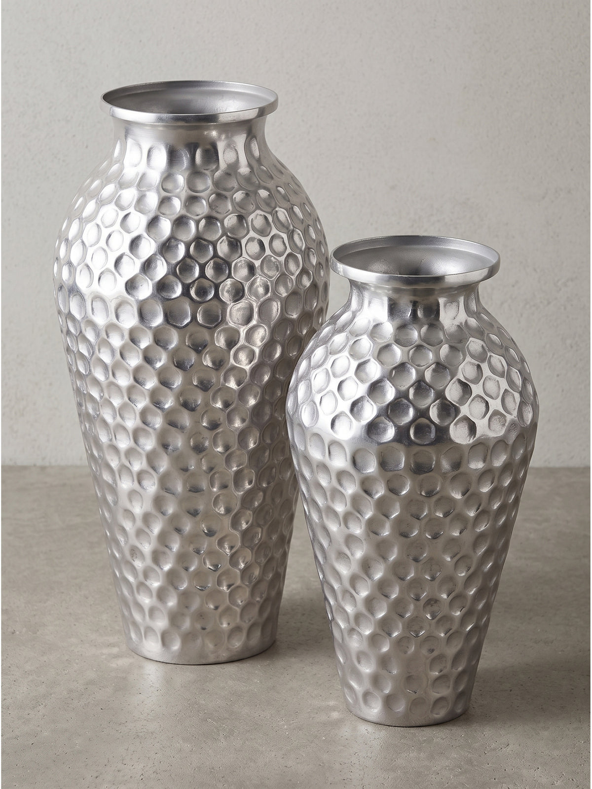 Detaillierter Blick auf die handwerkliche Verarbeitung und die lebendige Reflexion der gehämmerten Metalloberfläche des puristischen Wohnaccessoires.