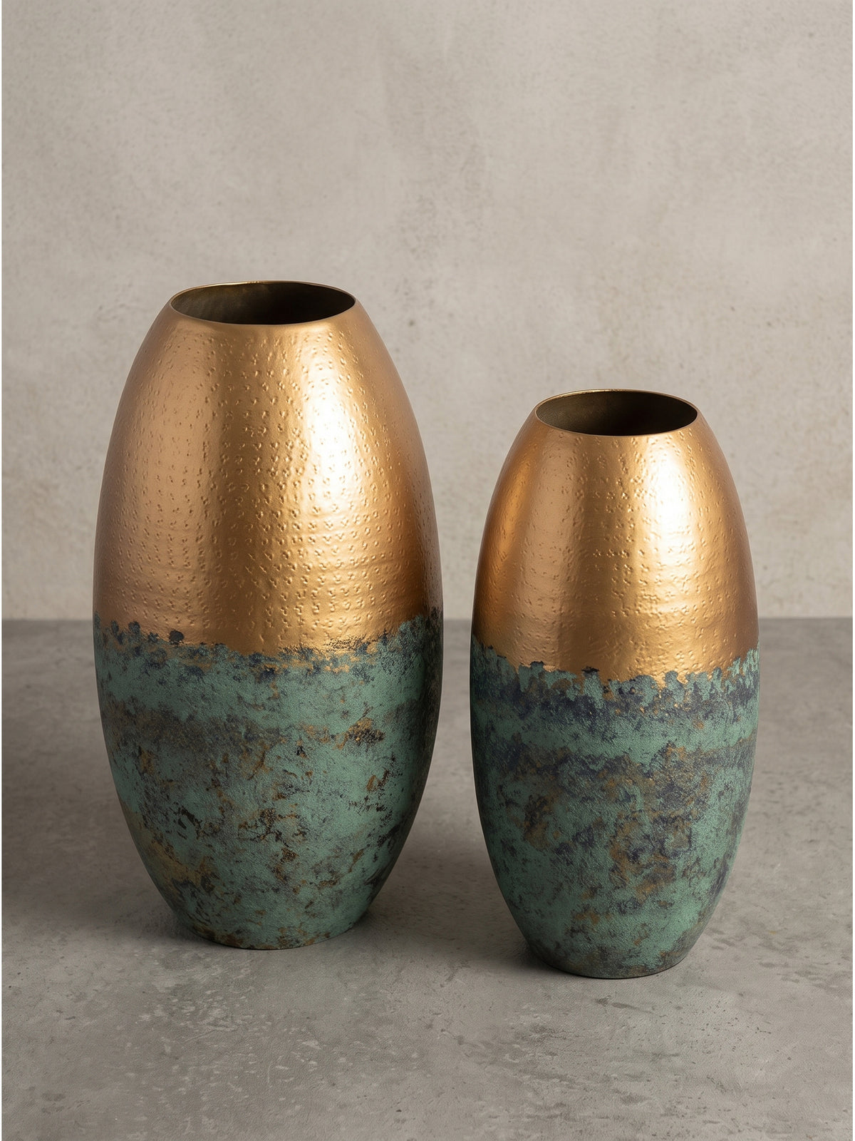 Makro-Detail des glatten Übergangs von der fein ziselierten goldenen Oberfläche zur rustikalen türkisgrünen oxidierten Patina der schweren Metall-Vase._