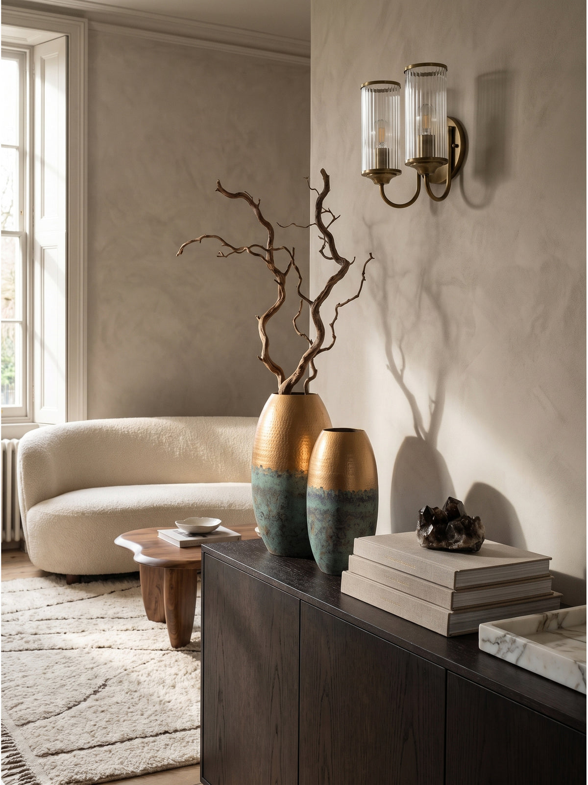 Die beiden ovalen Metallvasen in 47 cm und 40 cm Höhe stehen harmonisch als Duo neben einer Keramik-Tischlampe vor einer gekalkten Wand im eleganten Esszimmer.