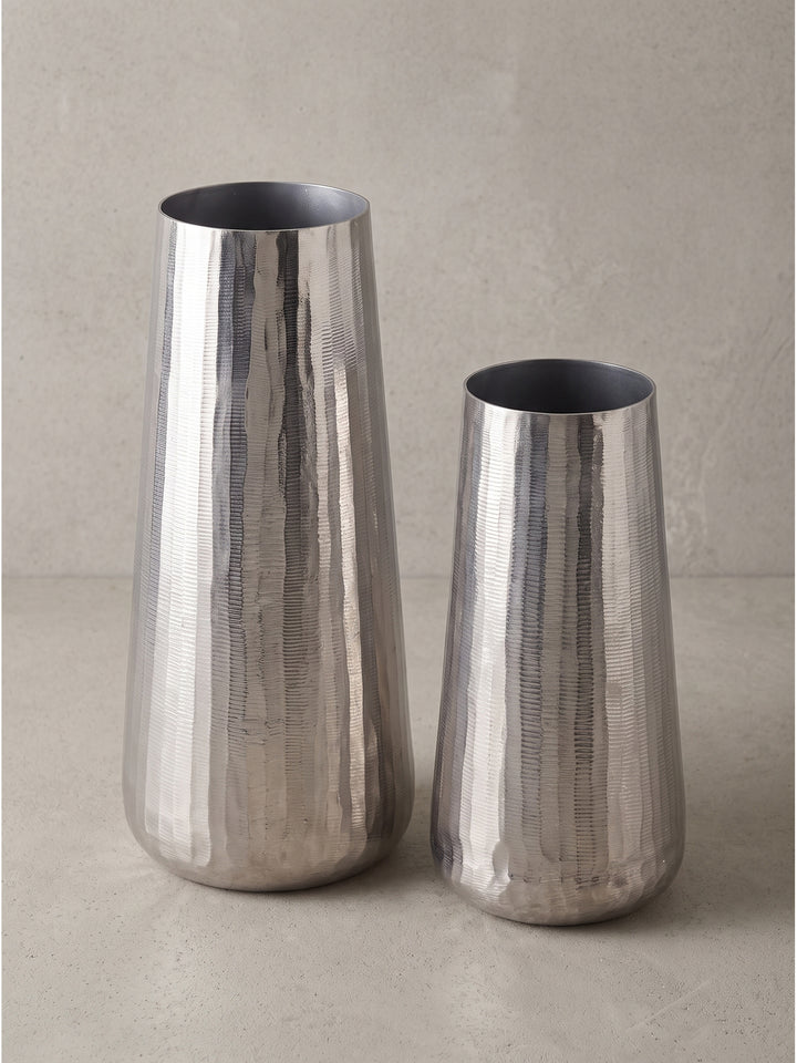 Zwei zylindrische und leicht konische Vasen aus massivem silber lackiertem Aluminium freigestellt vor weißem Hintergrund._