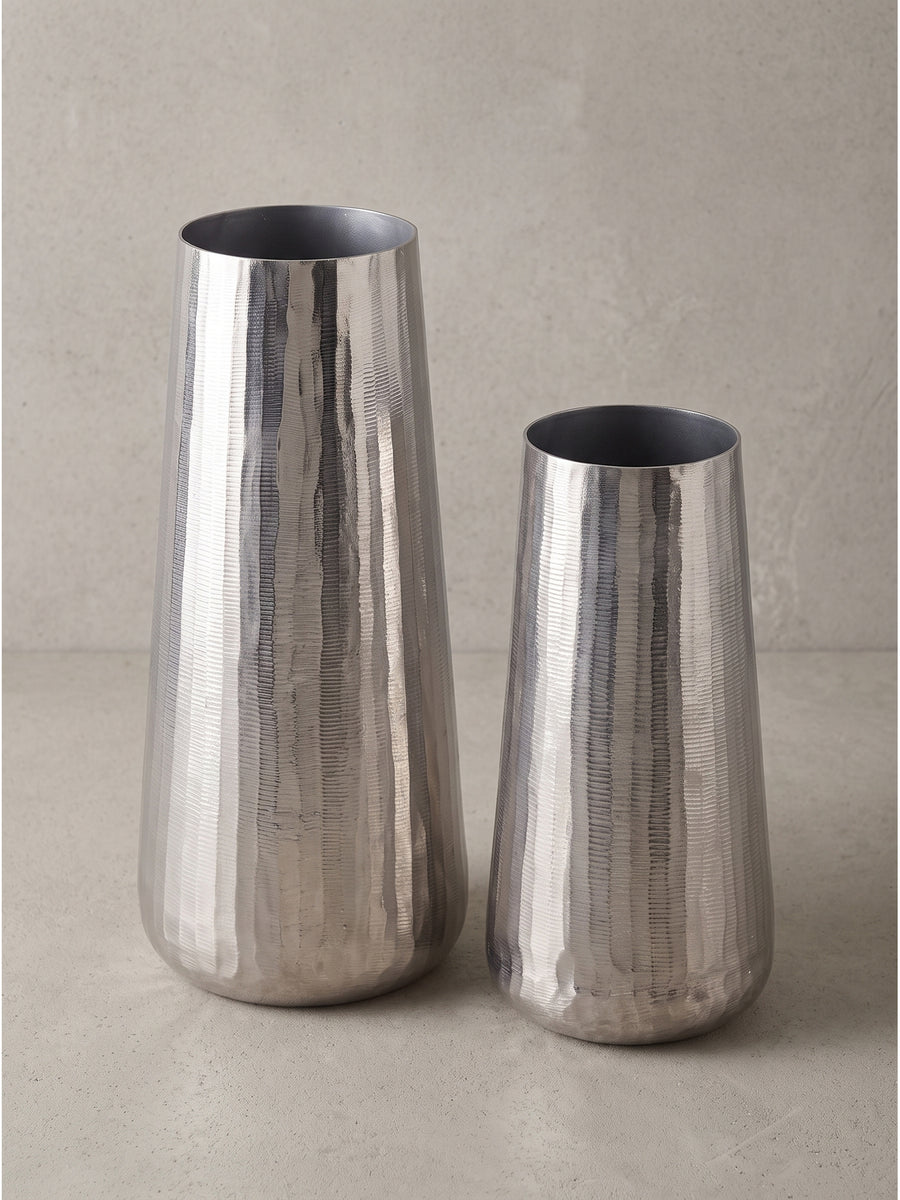 Zwei zylindrische und leicht konische Vasen aus massivem silber lackiertem Aluminium freigestellt vor weißem Hintergrund._