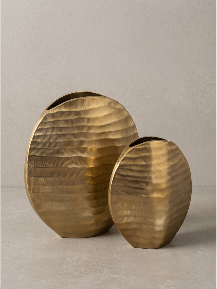 Nahaufnahme der strukturierten Kante der massiven goldfarbenen Metallvase, die den handgefertigten Charakter zeigt._