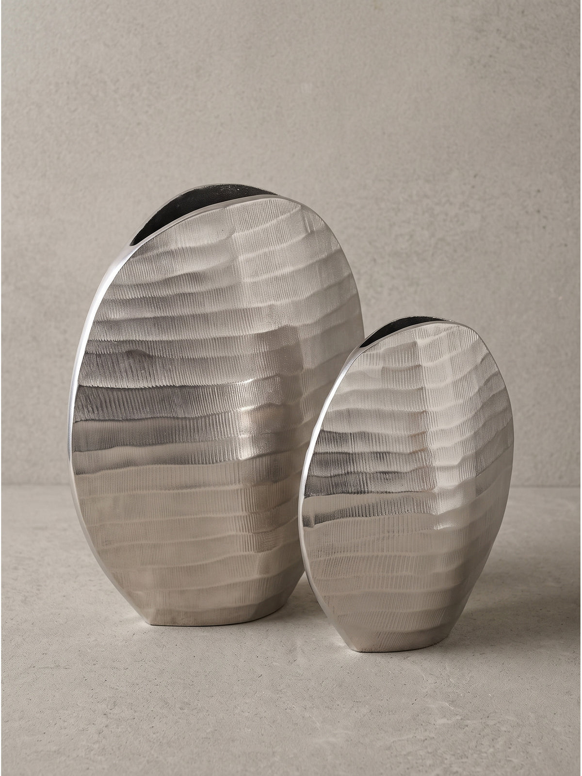 Frontale Studioaufnahme des zweiteiligen Sets runder Dekovasen aus massivem Aluminium mit silbernem Finish._