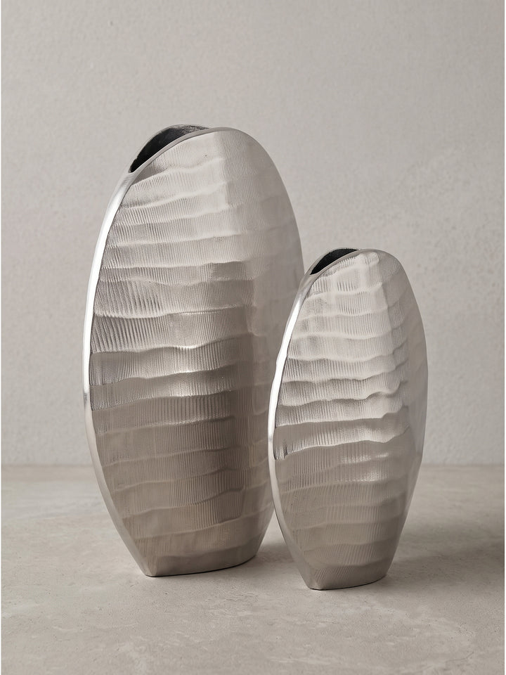 Die schmale, elliptische Form der handgearbeitet wirkenden Aluminiumvasen in der seitlichen Detailansicht._
