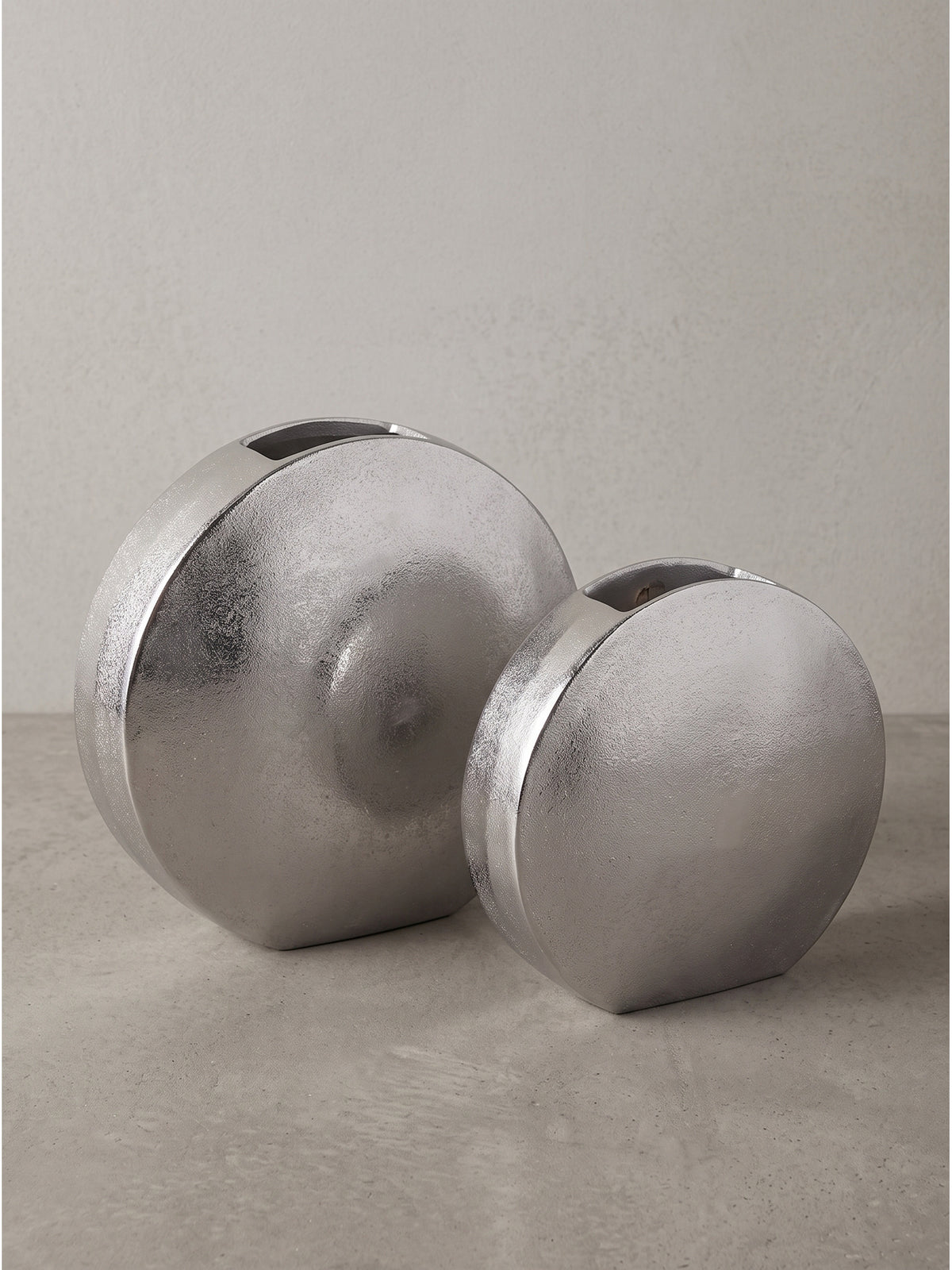 Detaillierte Oberflächenstruktur der silber lackierten Aluminiumvase mit feinen unregelmäßigen Lichtreflexionen.