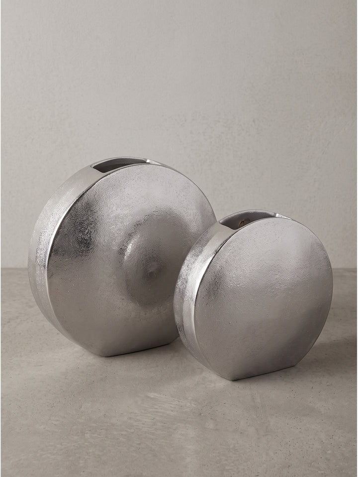 Detaillierte Oberflächenstruktur der silber lackierten Aluminiumvase mit feinen unregelmäßigen Lichtreflexionen._