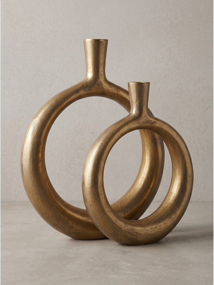 Profilansicht der massiven goldenen Metallvasen mit ihrer charakteristischen kreisrunden Öffnung im minimalistischen Design_