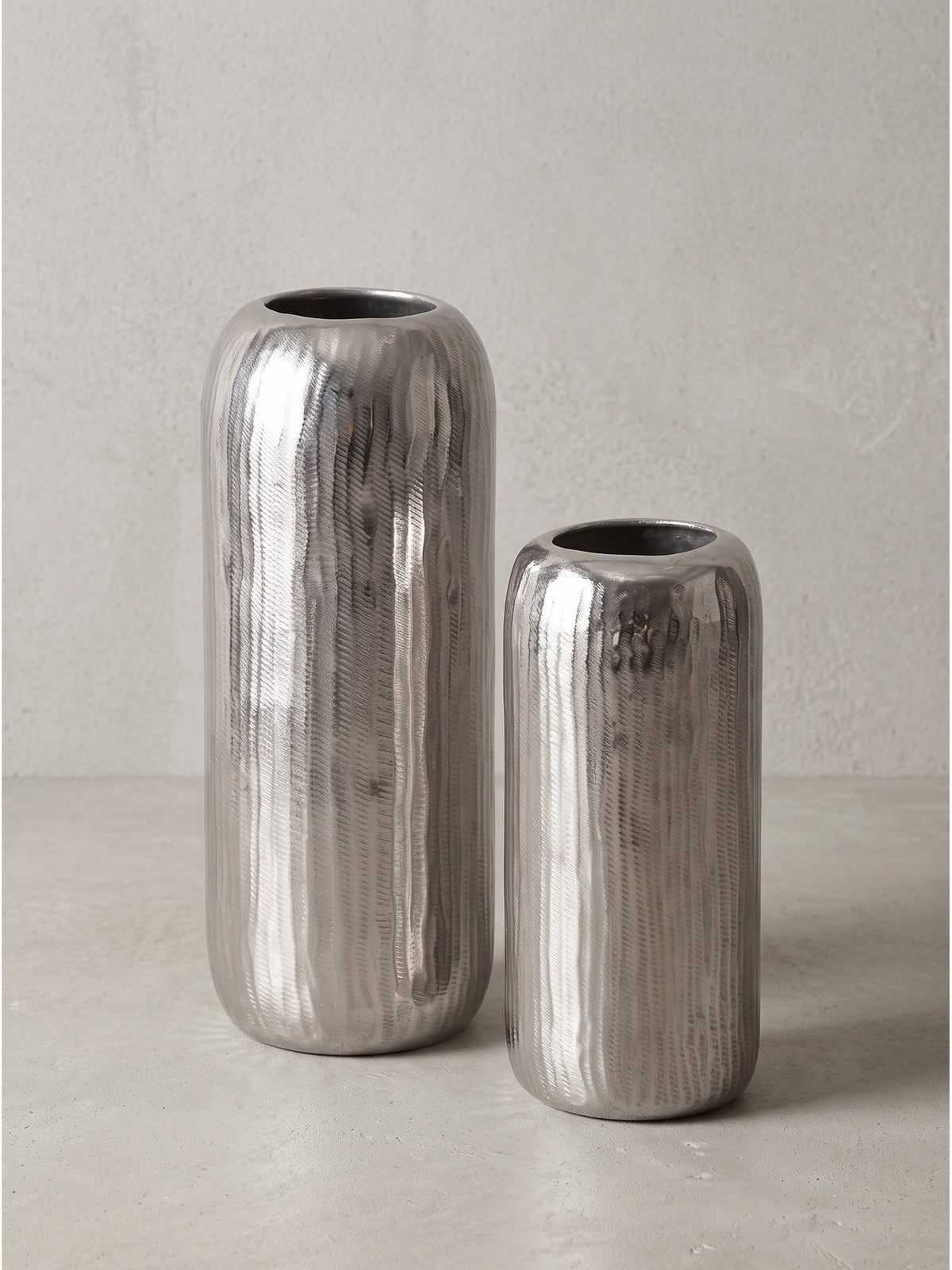 Silberne Deko Vase aus Aluminium als elegantes 2er Set in Zylinderform freigestellt vor neutralem Hintergrund._