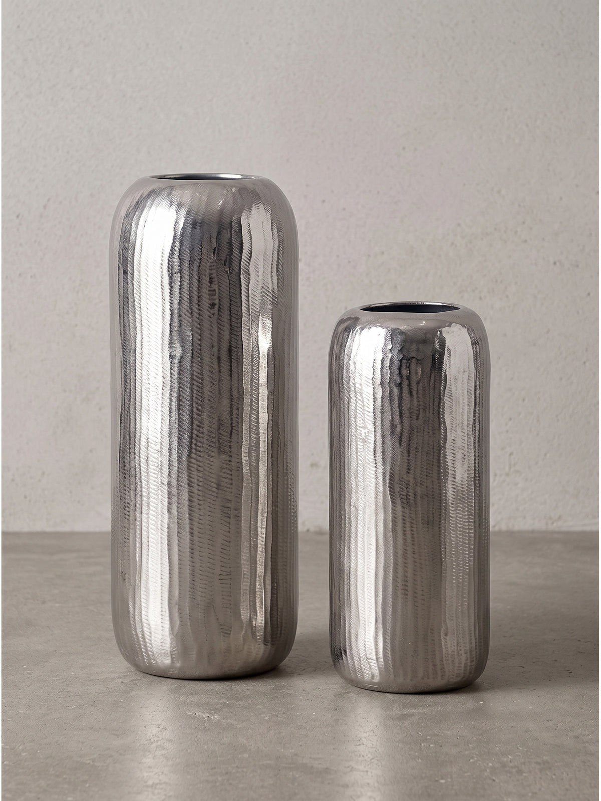 Profilansicht der runden Metallvasen mit 40 cm und 30 cm Höhe und glänzender Riffelstruktur._