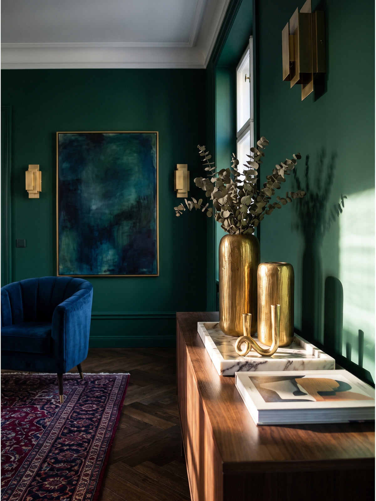 Goldene Aluminium Vasen 2-teilig arrangiert mit abstrakter Kunst und dunklen Büchern in einem luxuriösen Interieur_