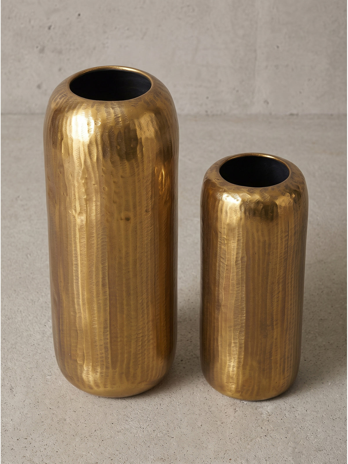 Seitliche Ansicht der zylindrischen goldenen Dekovasen aus massivem Aluminium mit sichtbarer Oberflächenstruktur_
