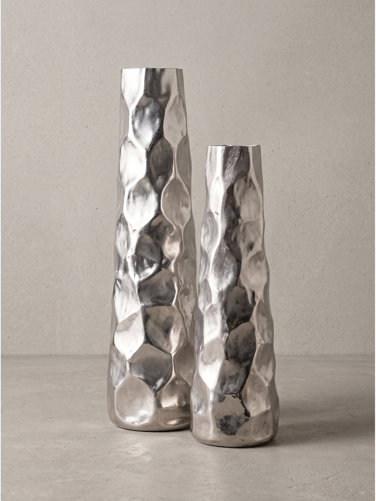 Schlanke Blumenvase aus gebürstetem Aluminium in Seitenansicht mit unregelmäßiger facettenreicher Silhouette_
