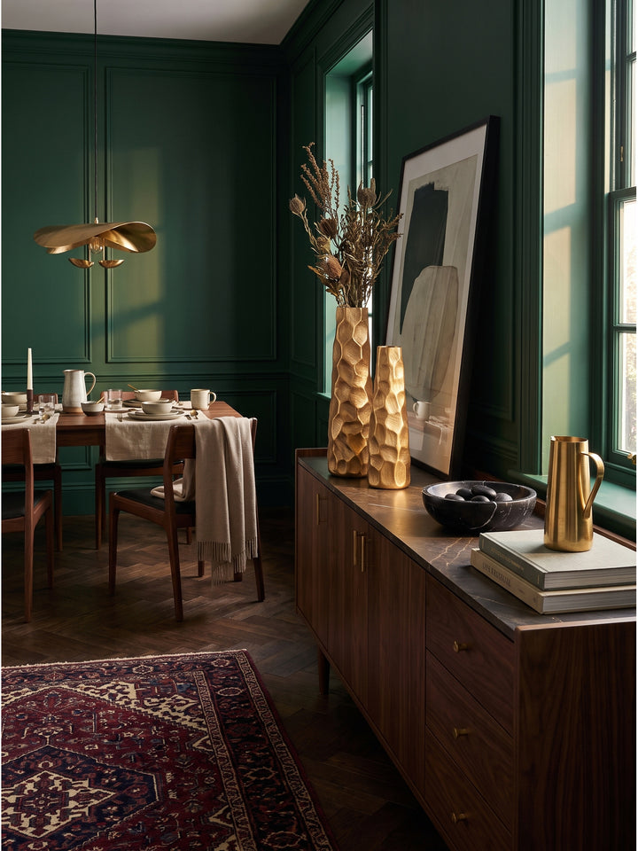 Goldenes Vasen-Set 2-teilig kombiniert mit abstrakter Kunst und einem cremefarbenen Samtsessel im eleganten Wohnbereich_