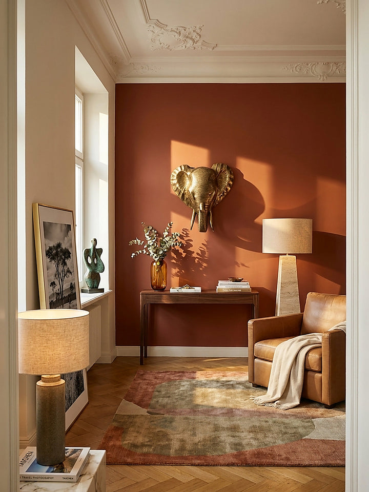 Elegante Wanddekoration als goldener Elefantenkopf aus massivem Aluminium an einer tiefgrünen Akzentwand im luxuriösen Wohnzimmer._