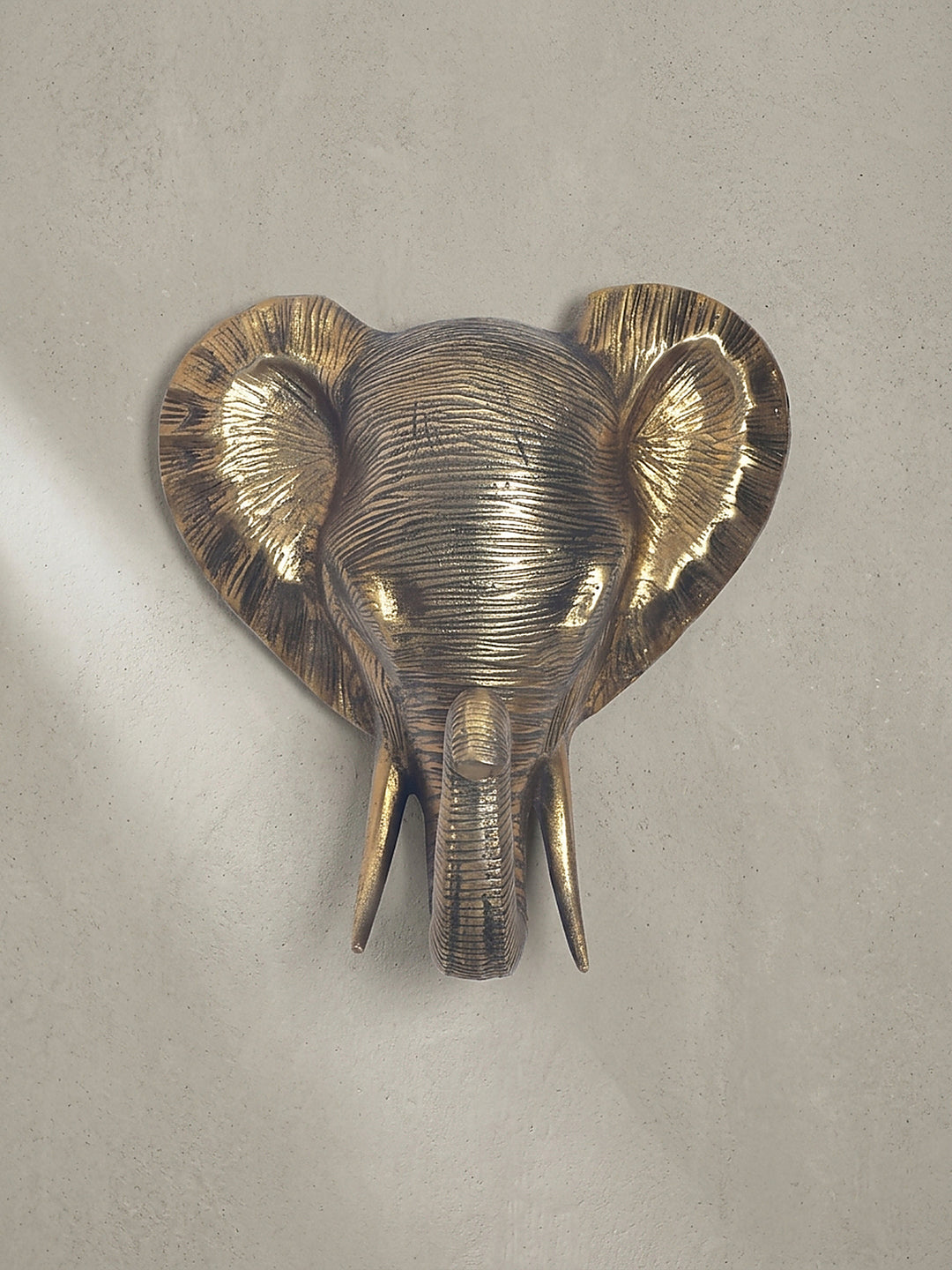 Frontale Ansicht der 33x20x41 cm großen Wanddeko als Elefantenkopf aus massivem, goldfarben lackiertem Aluminium._