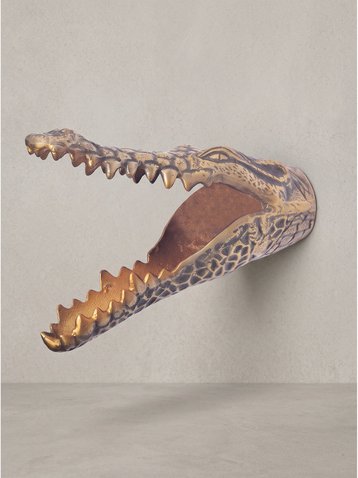 Handgefertigte Wandskulptur Krokodilkopf in Antik-Gold vor dunklem Hintergrund, Ansicht von schräg vorne mit Fokus auf die Struktur_