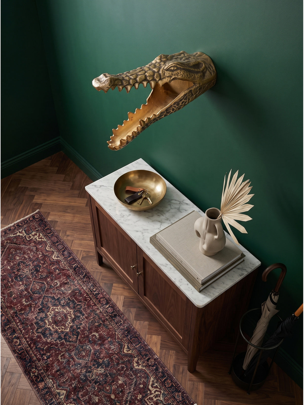 Aufsicht auf den Flur mit der handgefertigten goldenen Krokodilskulptur an der grünen Wand, umgeben von Art-Deco-Wandleuchten und einem Burgunder-Läufer_