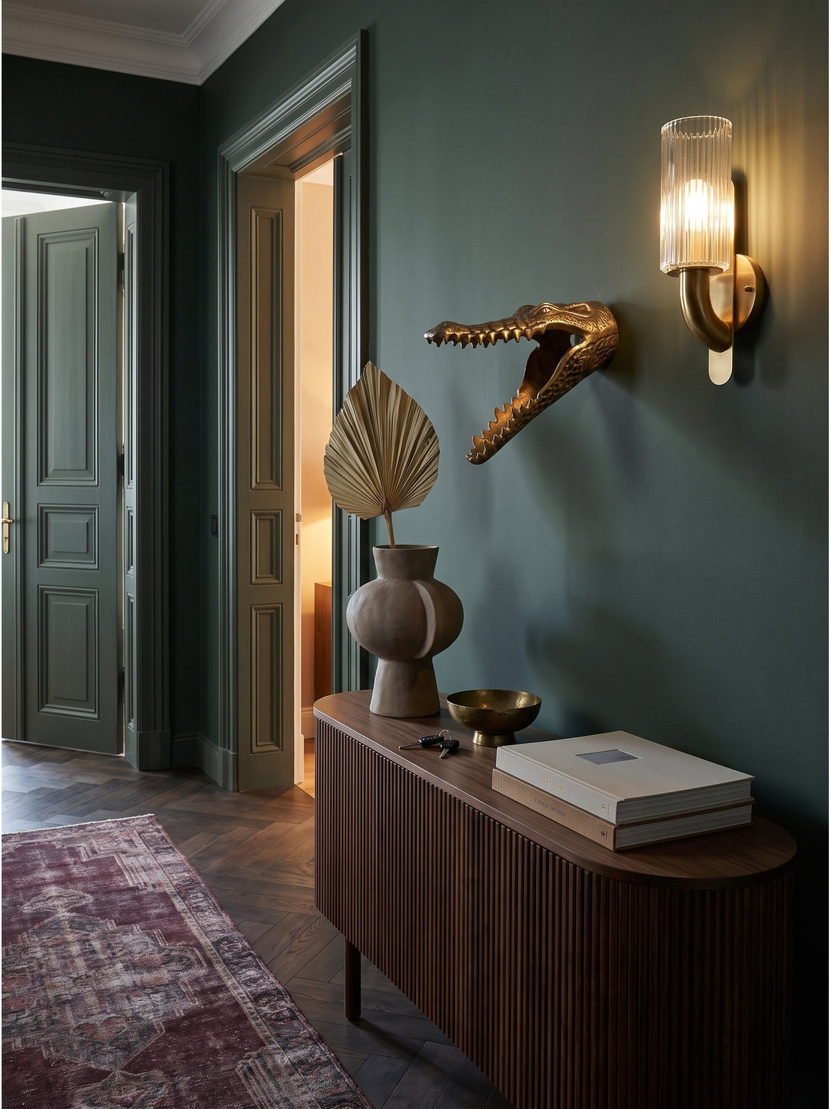 Die exotische Krokodil Wanddekoration in Gold harmoniert perfekt mit dunklem Walnussparkett und eleganten Art-Deco-Elementen im herrschaftlichen Flur_