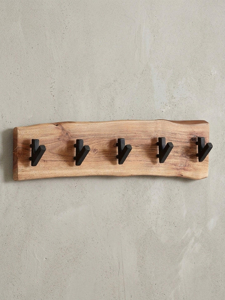 Frontalansicht der Wandgarderobe mit einzigartiger Baumkante aus massivem Akazienholz und fünf robusten, schwarzen Metallhaken, Maße 60 x 17 cm._
