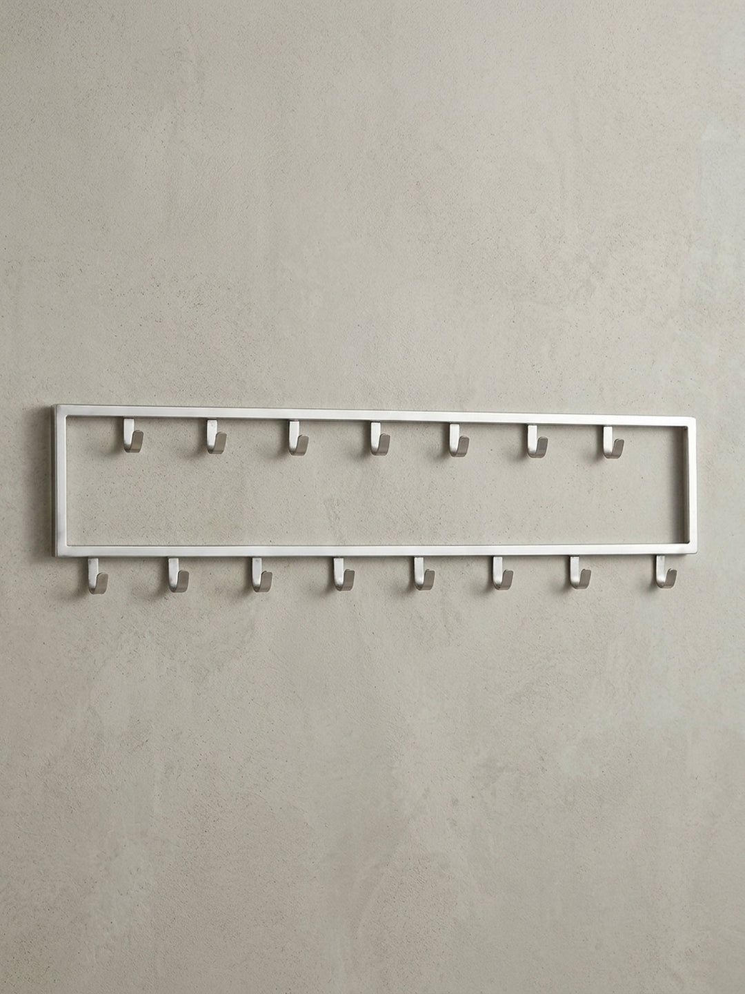 Frontalansicht der Wandgarderobe aus silbernem Stahl, 80x20 cm, mit ihrer klaren, rechteckigen Form und den 15 versetzten Haken._