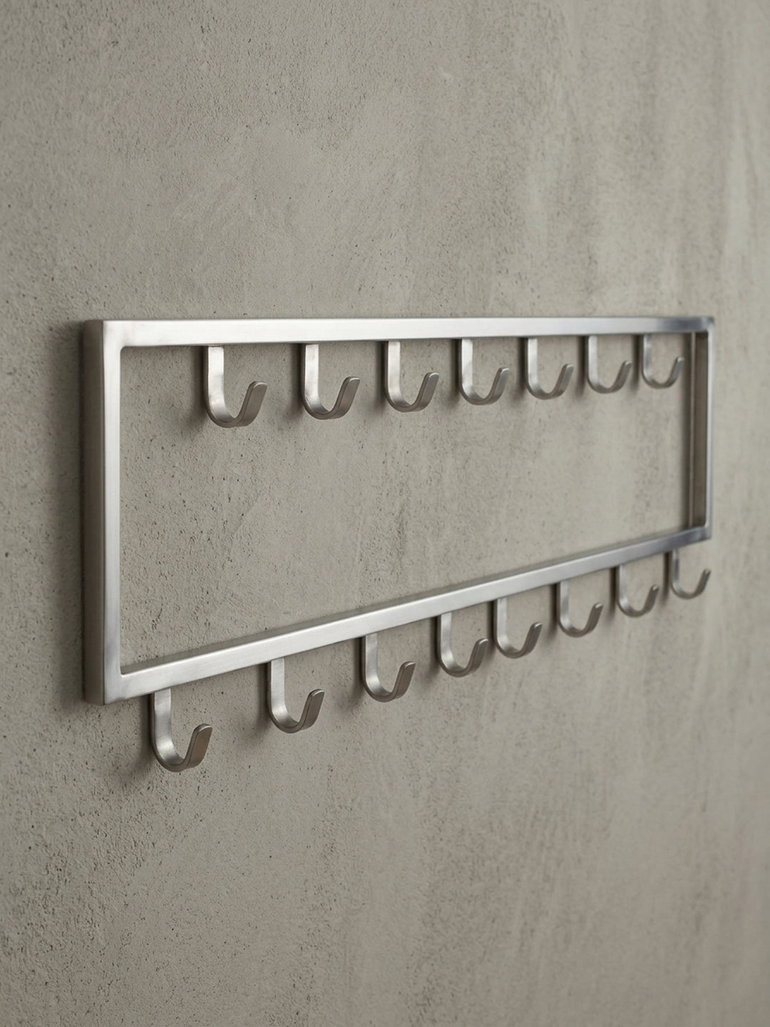 Makro-Detail eines einzelnen Hakens der silbernen Wandgarderobe, der die abgerundete Form und die Belastbarkeit der Stahlkonstruktion verdeutlicht._