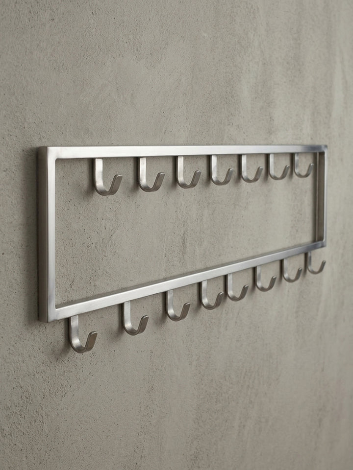 Makro-Detail eines einzelnen Hakens der silbernen Wandgarderobe, der die abgerundete Form und die Belastbarkeit der Stahlkonstruktion verdeutlicht._