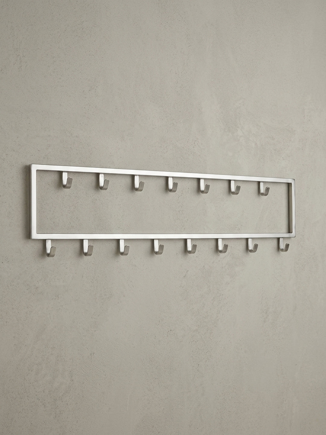 Seitenansicht des Wandpaneels, die das schlanke 4 cm Profil der Stahl-Garderobe und die Form der robusten Metallhaken hervorhebt._