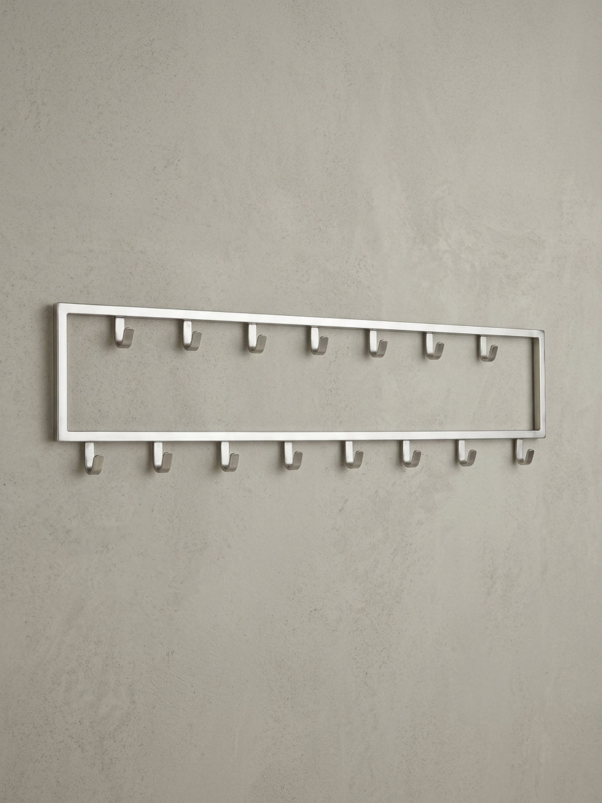 Seitenansicht des Wandpaneels, die das schlanke 4 cm Profil der Stahl-Garderobe und die Form der robusten Metallhaken hervorhebt.