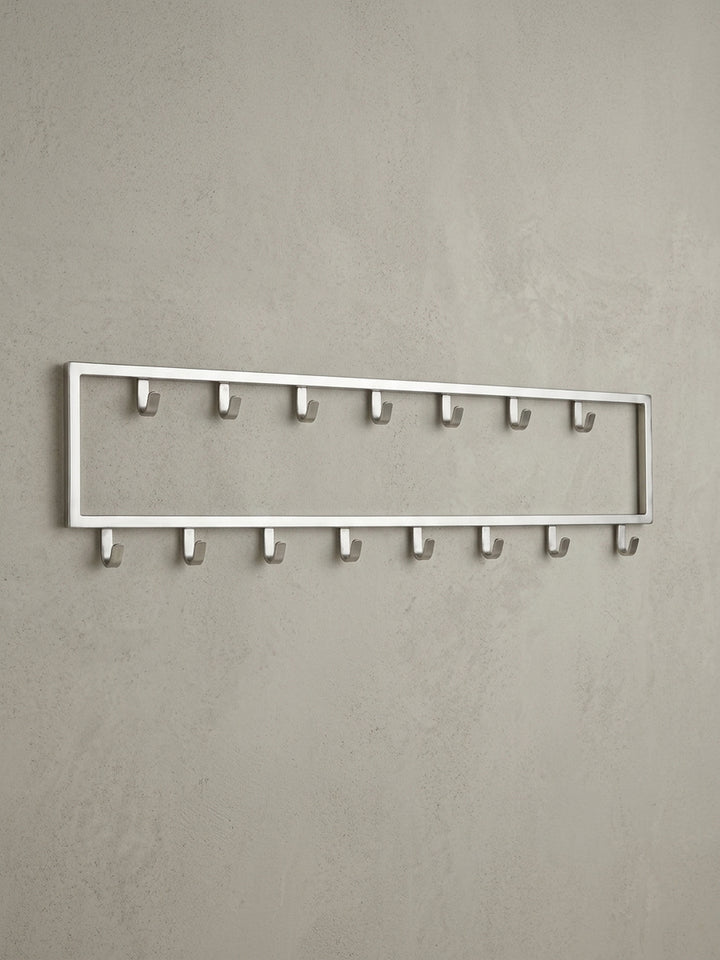 Seitenansicht des Wandpaneels, die das schlanke 4 cm Profil der Stahl-Garderobe und die Form der robusten Metallhaken hervorhebt._