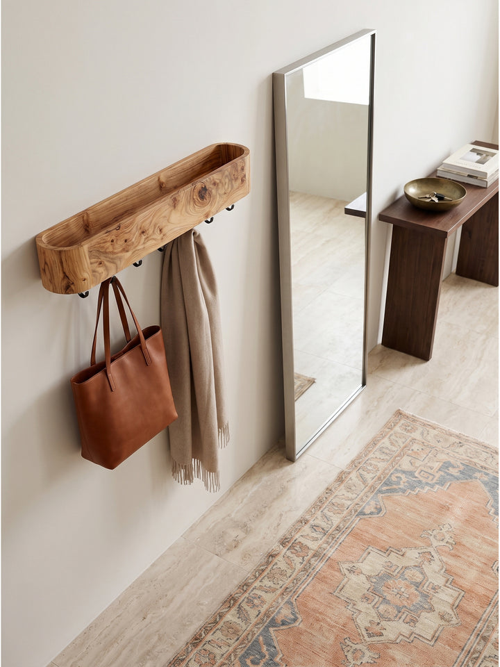 Flurgarderobe Holz hängend montiert über einer massiven Eichenbank mit Dekorationen von oben betrachtet auf Kalksteinboden_