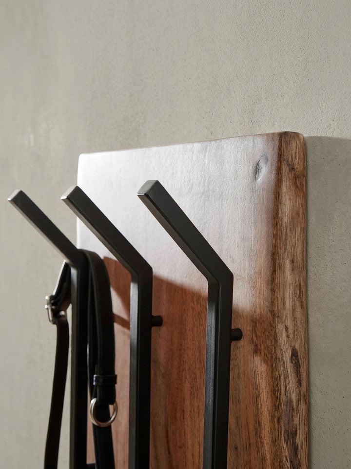 Perspektivische Ansicht der massiven Holzgarderobe, die das Zusammenspiel von der organischen Holzkante und den geradlinigen, geometrischen Haken aus Metall betont._