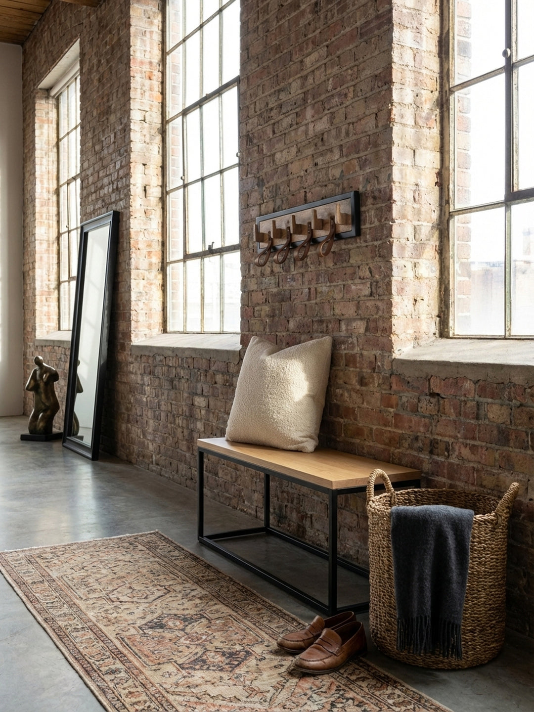 Die Wandgarderobe aus Mango-Massivholz und Leder in einem hellen, einladenden Altbau-Flur mit Dielenboden und einer Sitzbank._