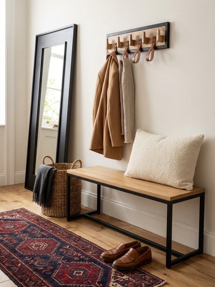 An der Flurgarderobe hängt ein leichter Trenchcoat neben einem Schal, der lässig durch eine der braunen Lederschlaufen gezogen ist._