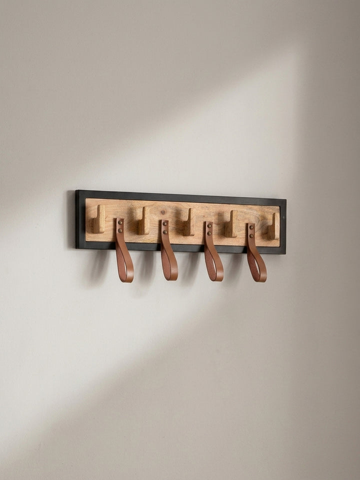 Dreiviertelansicht der Garderobenleiste aus Mangoholz, die Tiefe der Haken und die Anbringung der Lederschlaufen zeigend._